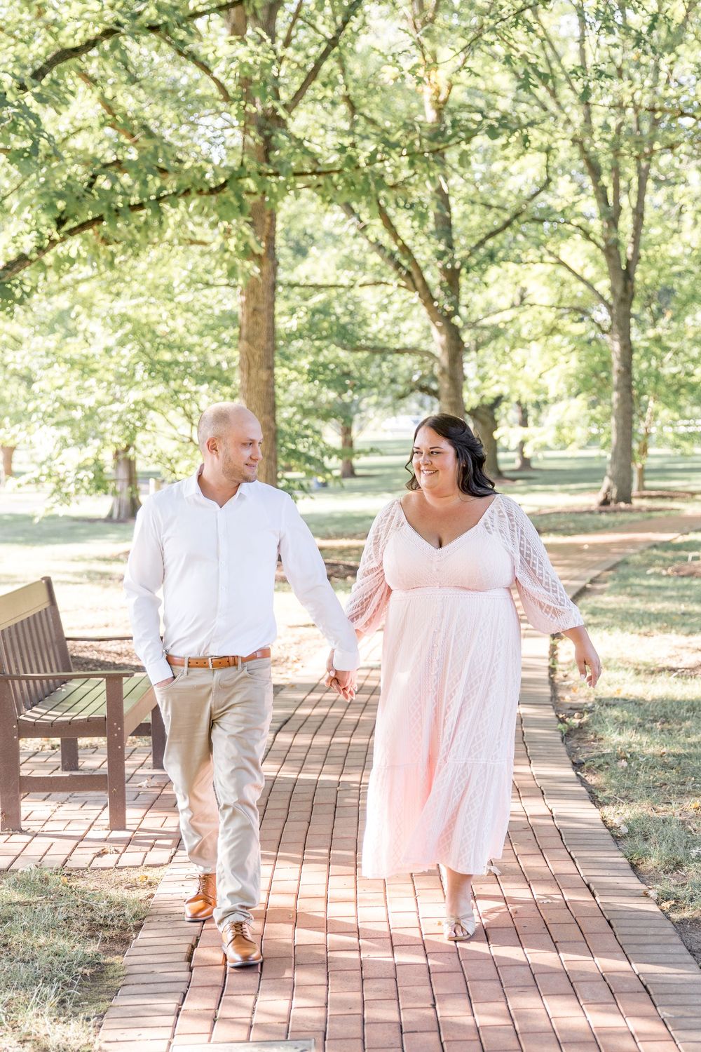 Loving couple dances together on a wooden deck in a garden setting with sunlit trees in the background.