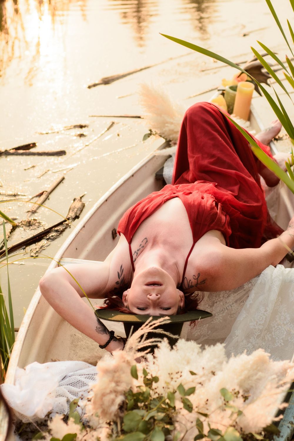 Person in red clothing rests peacefully by a tranquil waterside with reflective ripples and marsh grasses.