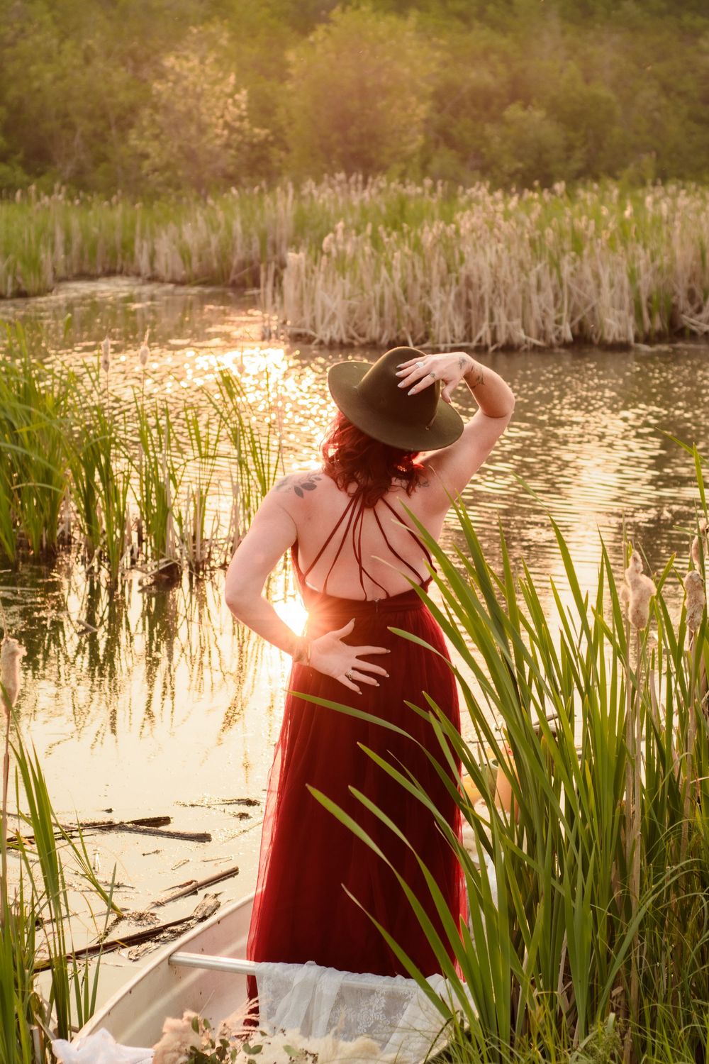 A person enjoying a tranquil moment by a serene pond with cattails and reeds during golden hour.