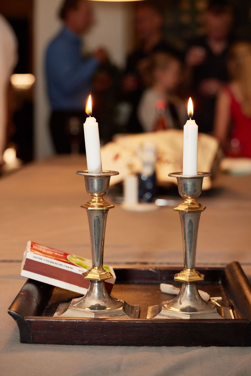 Lit Shabbat candles during Bat Mitzvah dinner. Elegant detail captured by George Robert Photography. Jewish tradition and warm atmosphere.