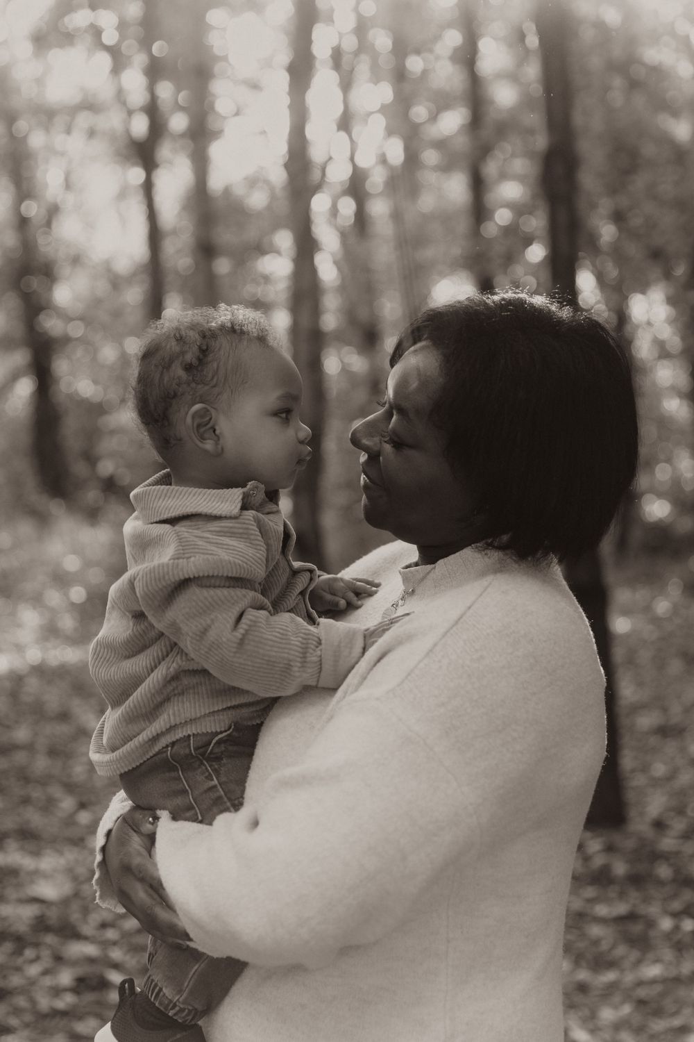 Black and white image sequence shows tender moments between parent and child in an autumn forest setting.