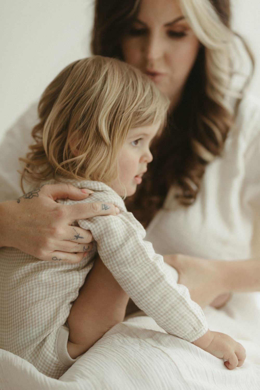 A small child in a checkered shirt sits close with a caregiver in soft, natural lighting.