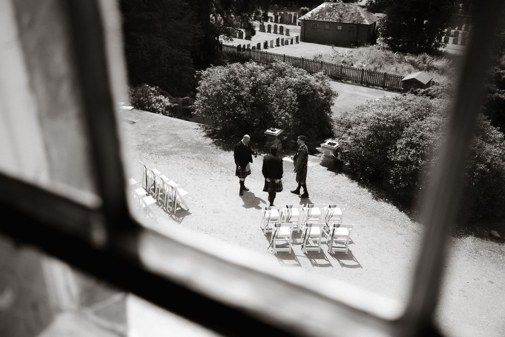 Black and white aerial view of people walking down a garden path with white chairs arranged outdoors.