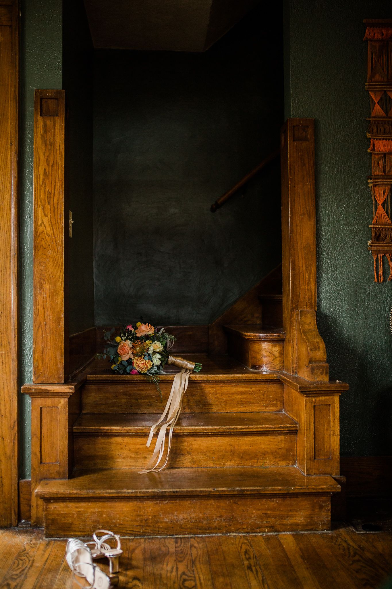 A vintage wooden staircase with a bridal bouquet and gloves resting on the steps in moody lighting.
