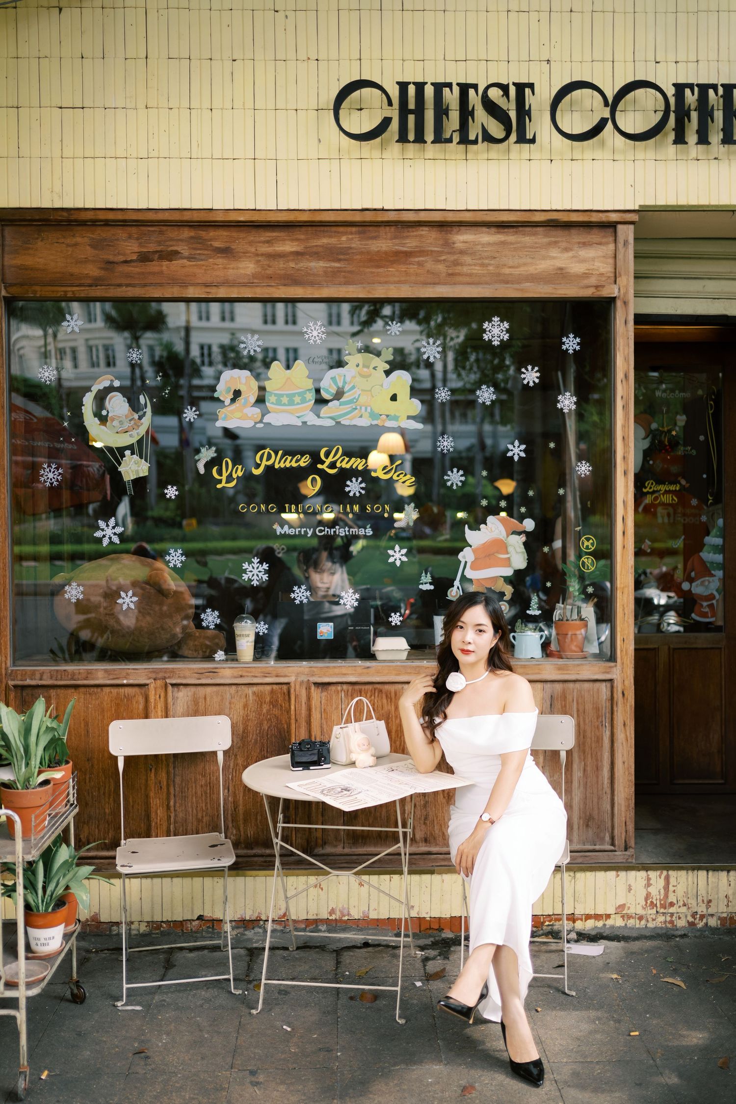 A charming cafe storefront with festive window decorations and outdoor seating beneath the Cheese Coffee sign.