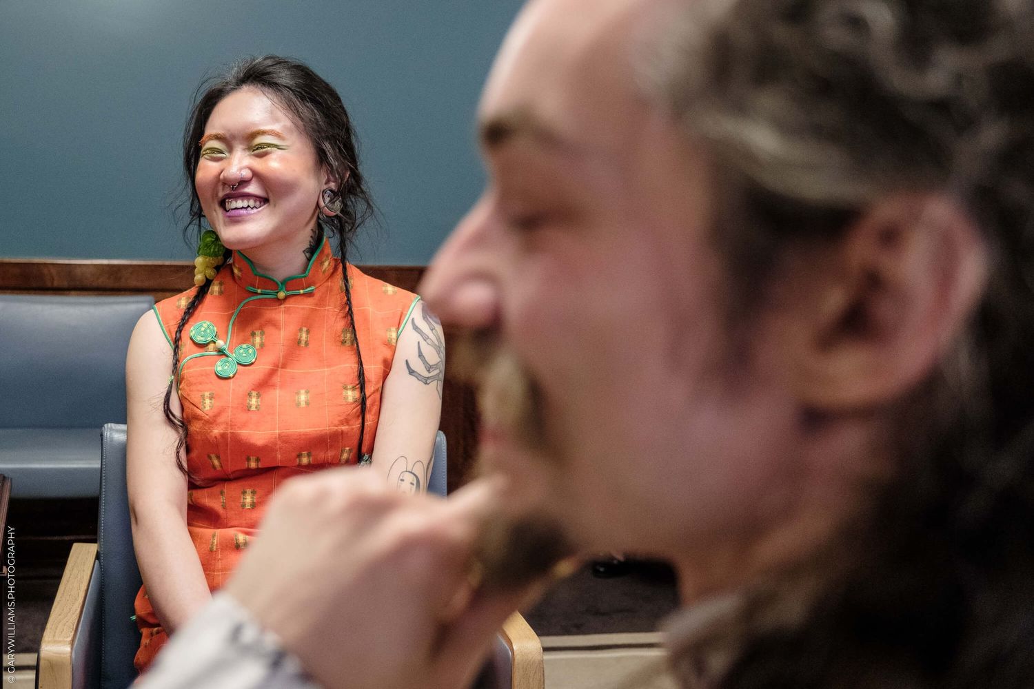 A couple engages in conversation and laughter while sitting together indoors.