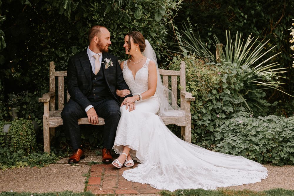 A couple shares a romantic moment together in a lush garden setting with the bride wearing a flowing white gown.