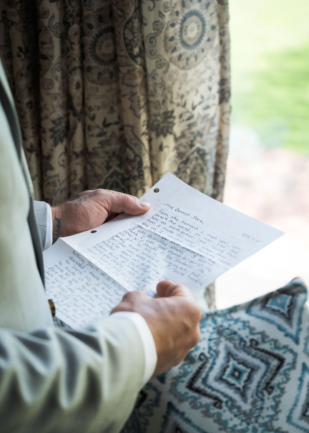 A handwritten letter or vows being read near a patterned curtain.