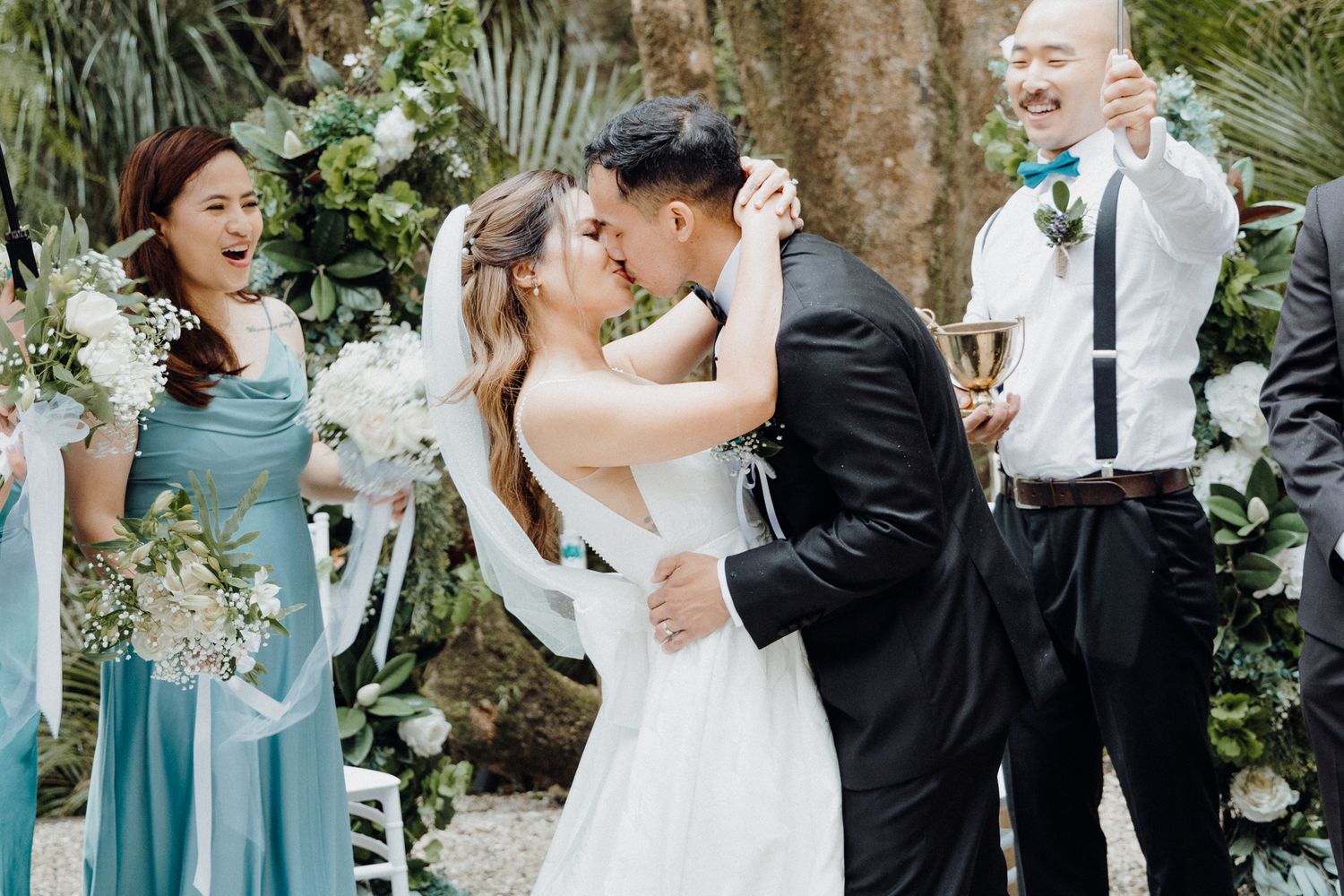 A romantic kiss during an outdoor garden wedding ceremony captured by Apertured Media Auckland Wedding Photographer.
