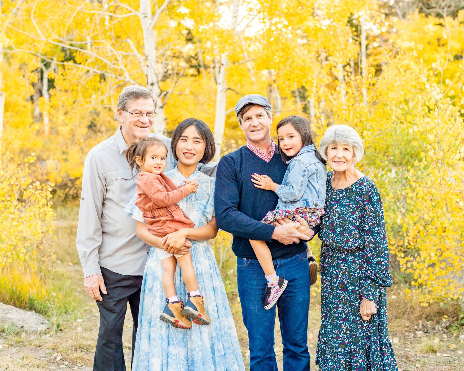 Family photo including grandparents in fall colored trees at a spot at the Alpine Loop.