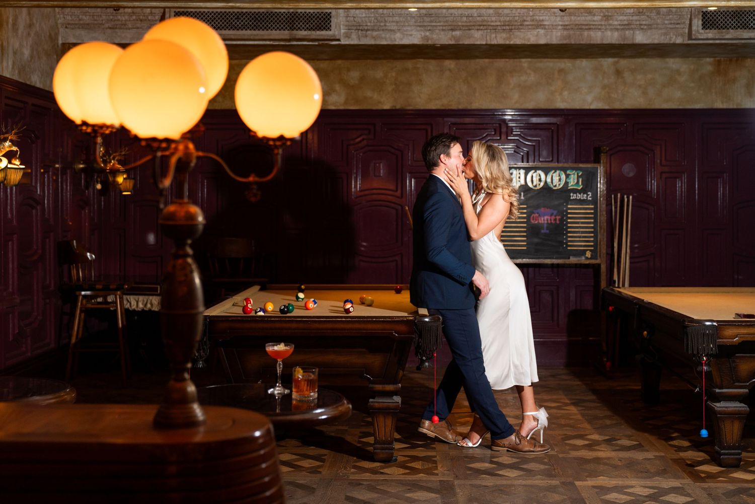Romantic dance scene in retro bar with glowing paper lanterns and pool table in background. Engagement Session at The Lafayette Hotel in San