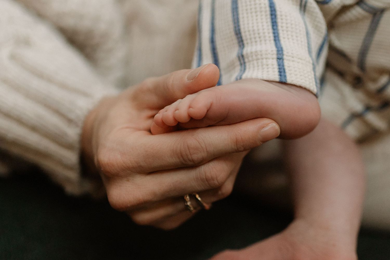 close up of intimate mother's hand holding her baby's foot