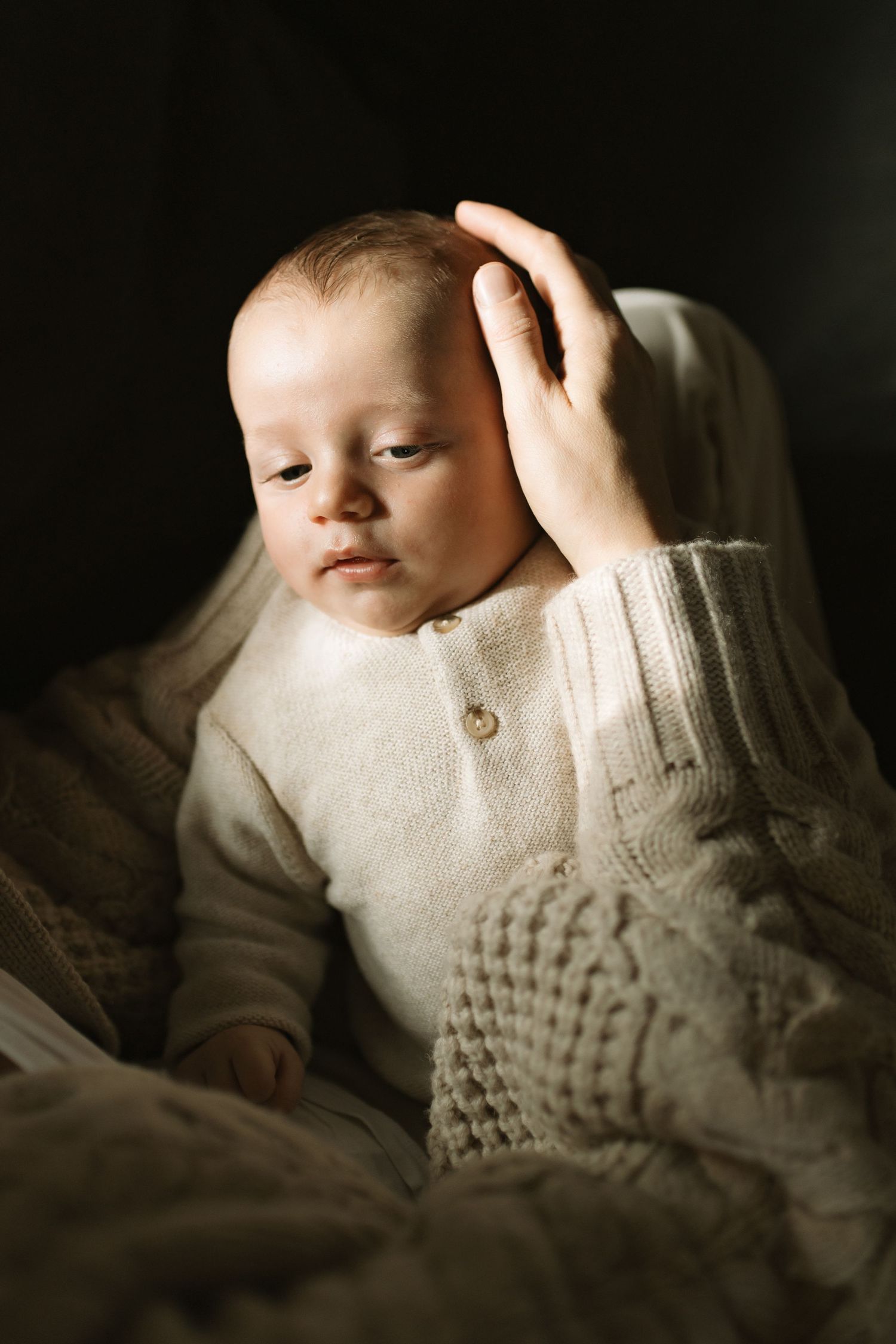 fine art photograph of newborn baby with his mother stroking his head