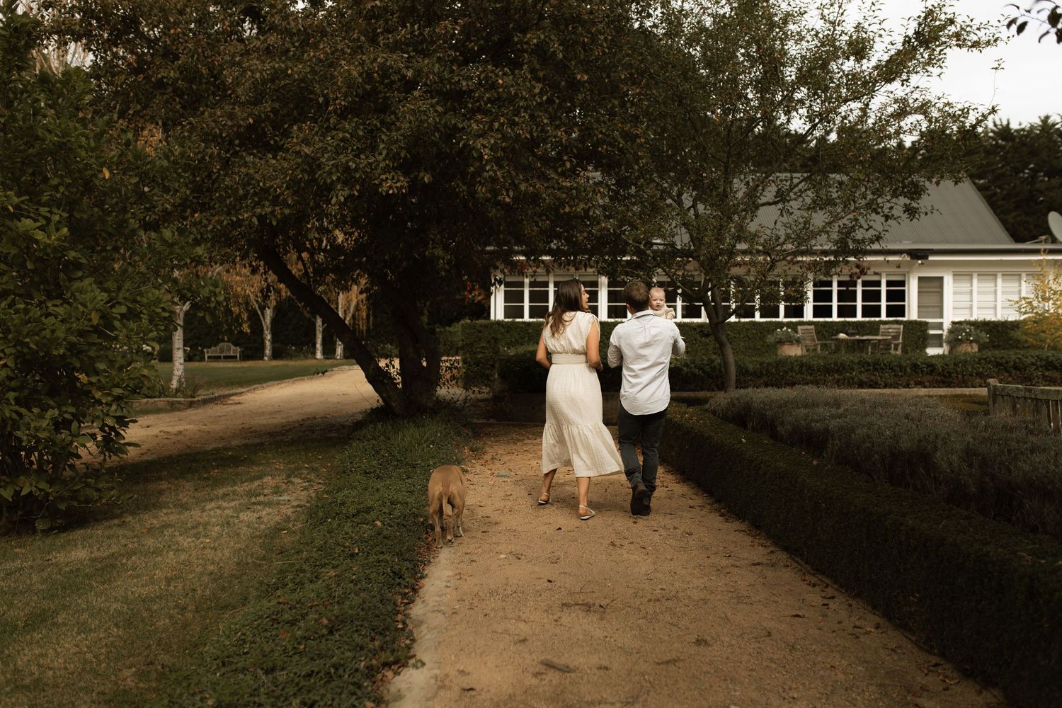 Mother father walking with their baby on their property in Autumn