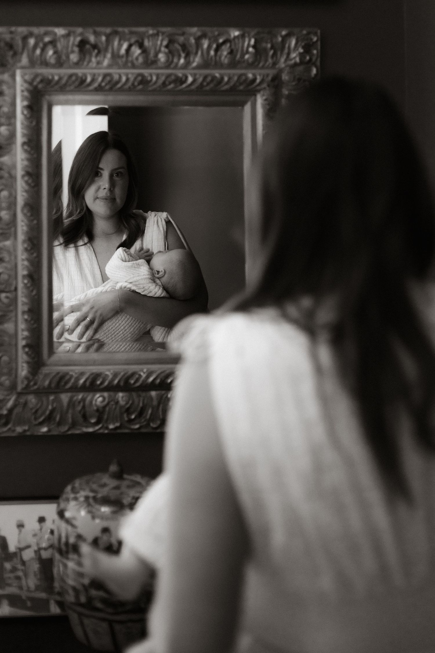 Newborn in home photography session, mother holding her baby looking into the mirror