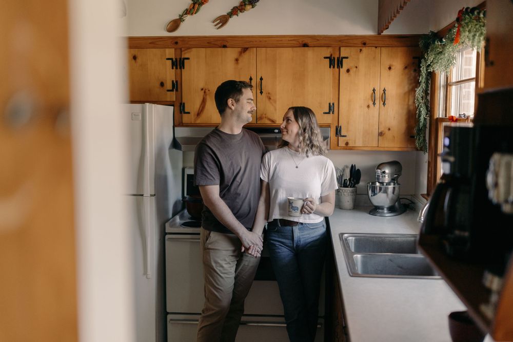 A romantic moment shared between two people in a cozy kitchen with wood paneling.