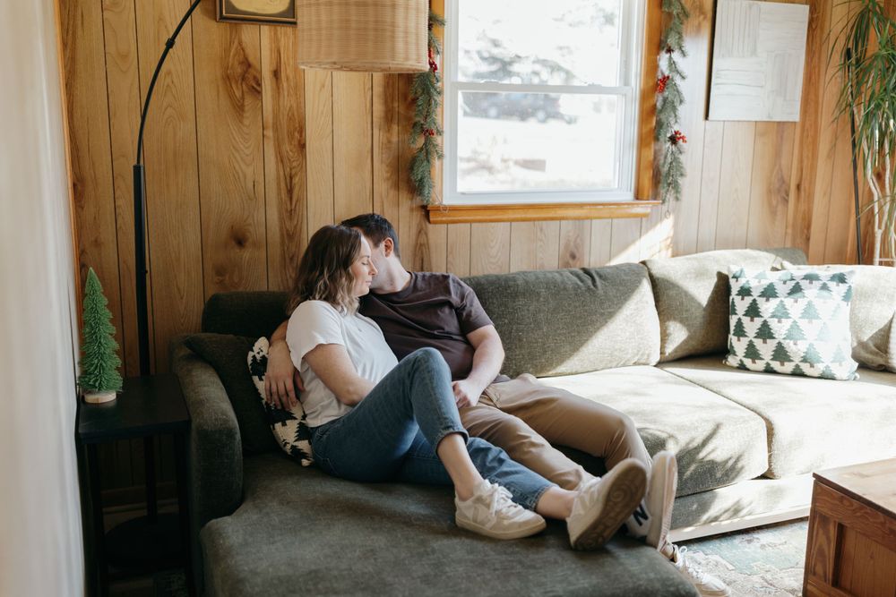 Cozy scene of a couple relaxing together on a grey sofa in a wood-paneled room.