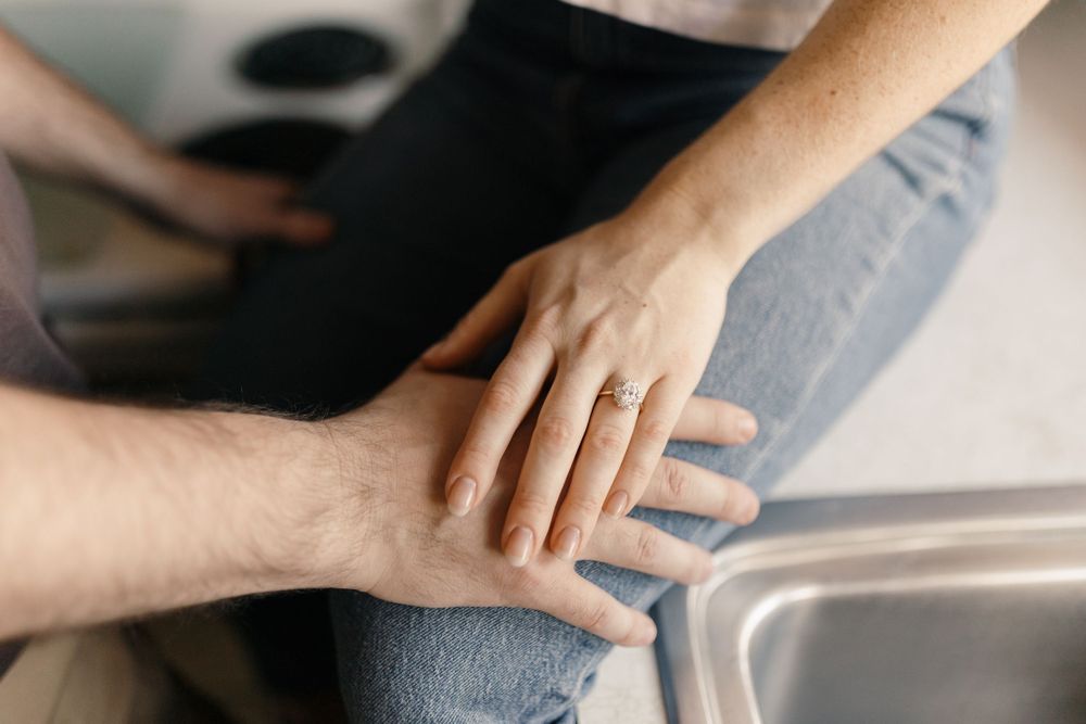 Close-up of hands touching tenderly on a kitchen counter.