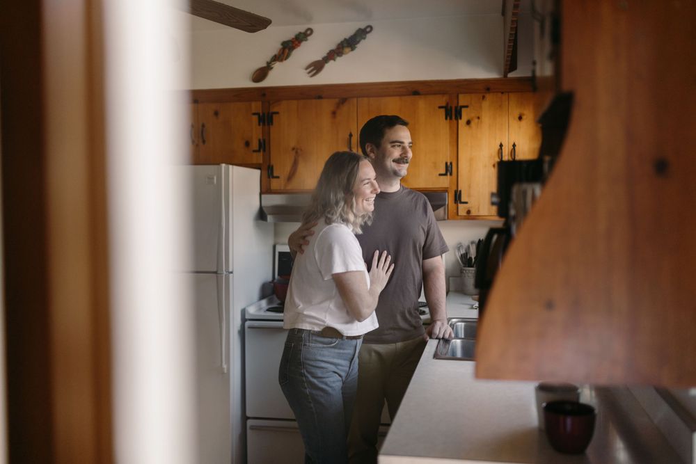 A couple sharing an intimate moment in a rustic kitchen with wood cabinets.