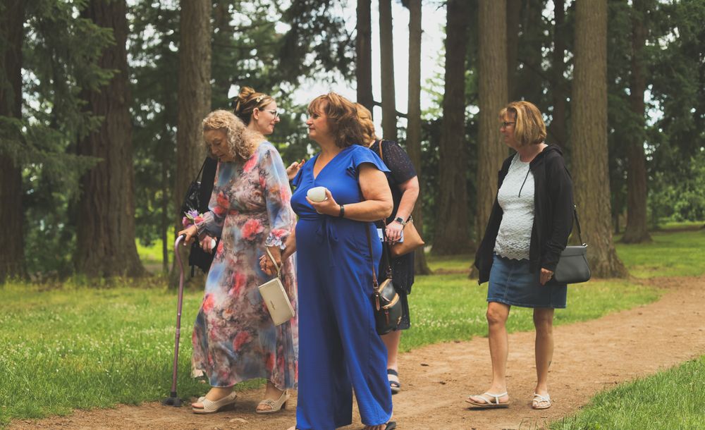 People enjoying a game of Ring Around the Rosie together in a park surrounded by tall trees.