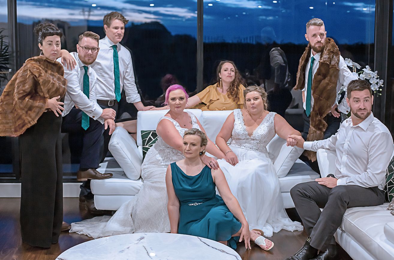Wedding guests relax on white couches at an evening reception against a dark sky backdrop.