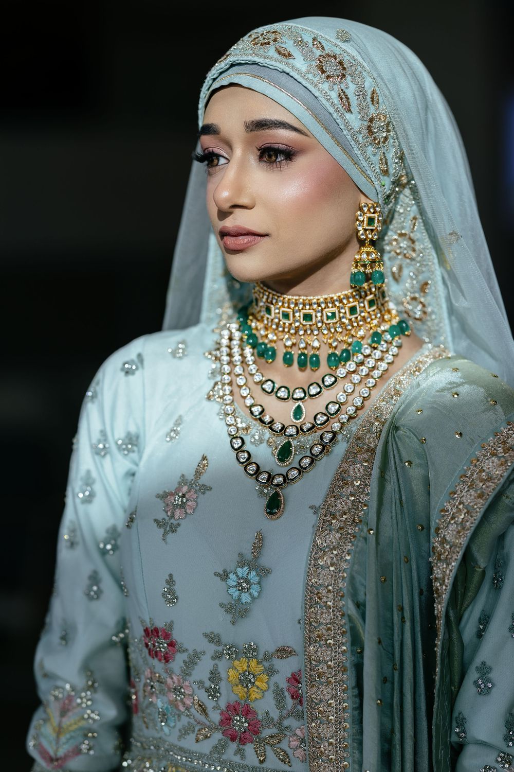 Traditional bridal ensemble featuring a mint dupatta with sequin work and statement kundan jewels with emerald stones.