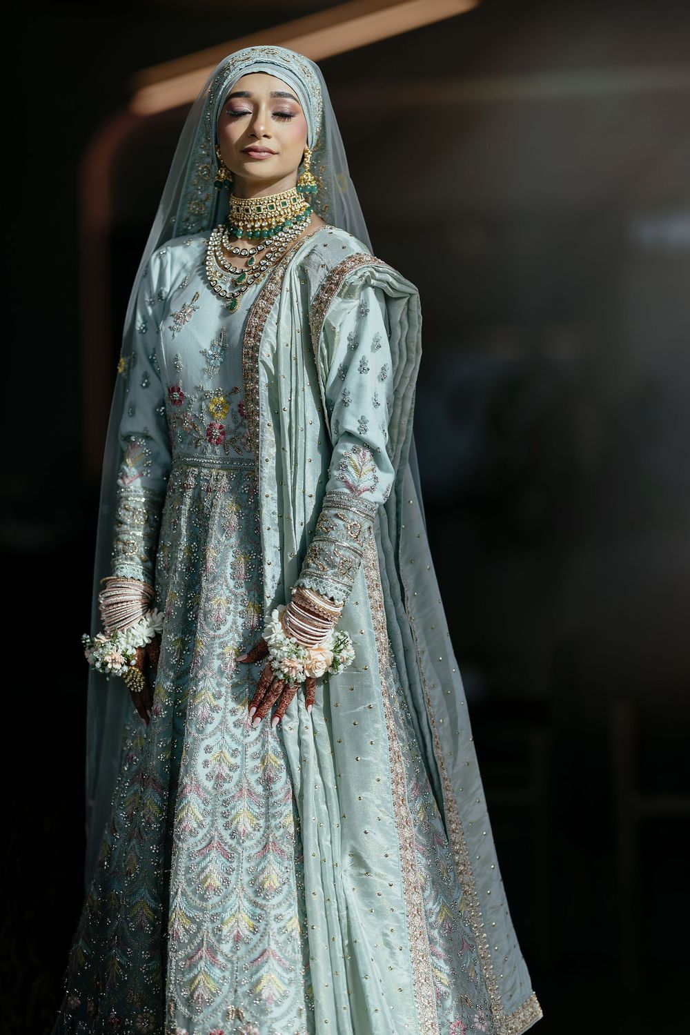 Traditional bridal attire in mint green with intricate floral embroidery and matching sheer veil.