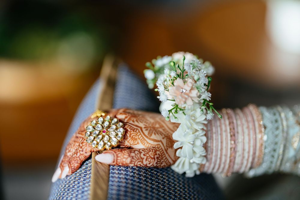 Close-up shot of traditional Indian bridal bangles with delicate white floral jewelry on dark textured surface.