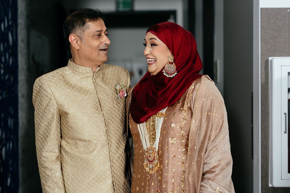 Brides parents in traditional Muslim attire share candid moments in candid wedding photography.