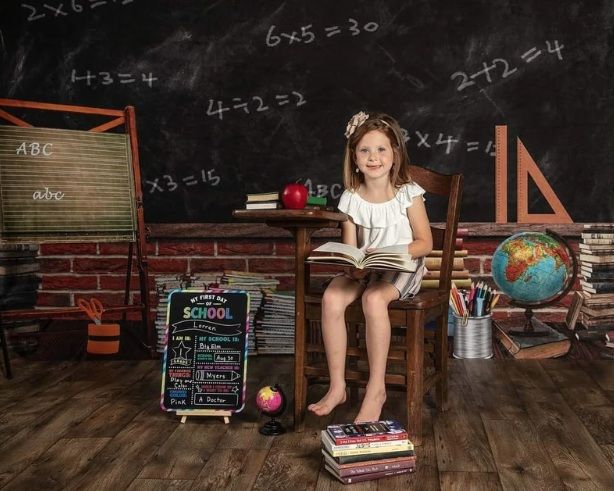 A child sits on stacked books against a chalkboard wall with educational decor, globe, and math equations surrounding them.