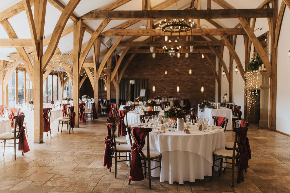 Rustic wooden barn venue decorated for wedding reception with round tables and elegant chandeliers.