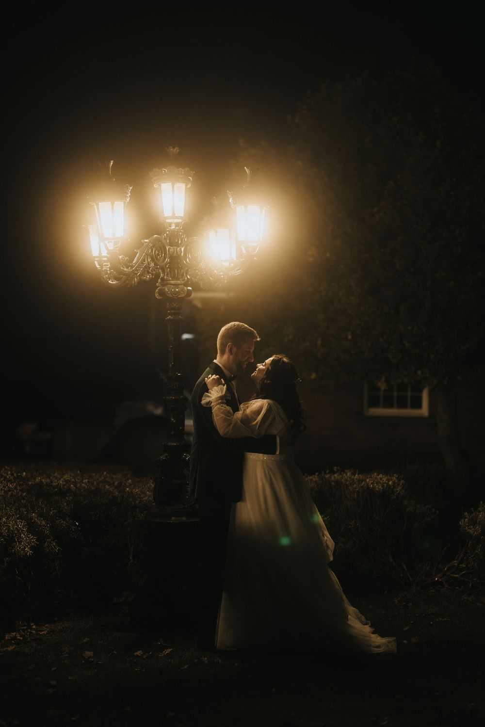 Romantic silhouette of a couple dancing under glowing vintage street lamps at night, creating a dreamy atmosphere.