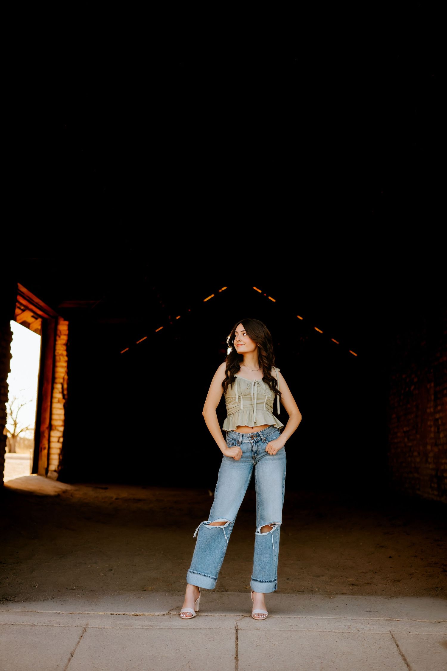 High school senior standing in rustic barn doorway in Arizona