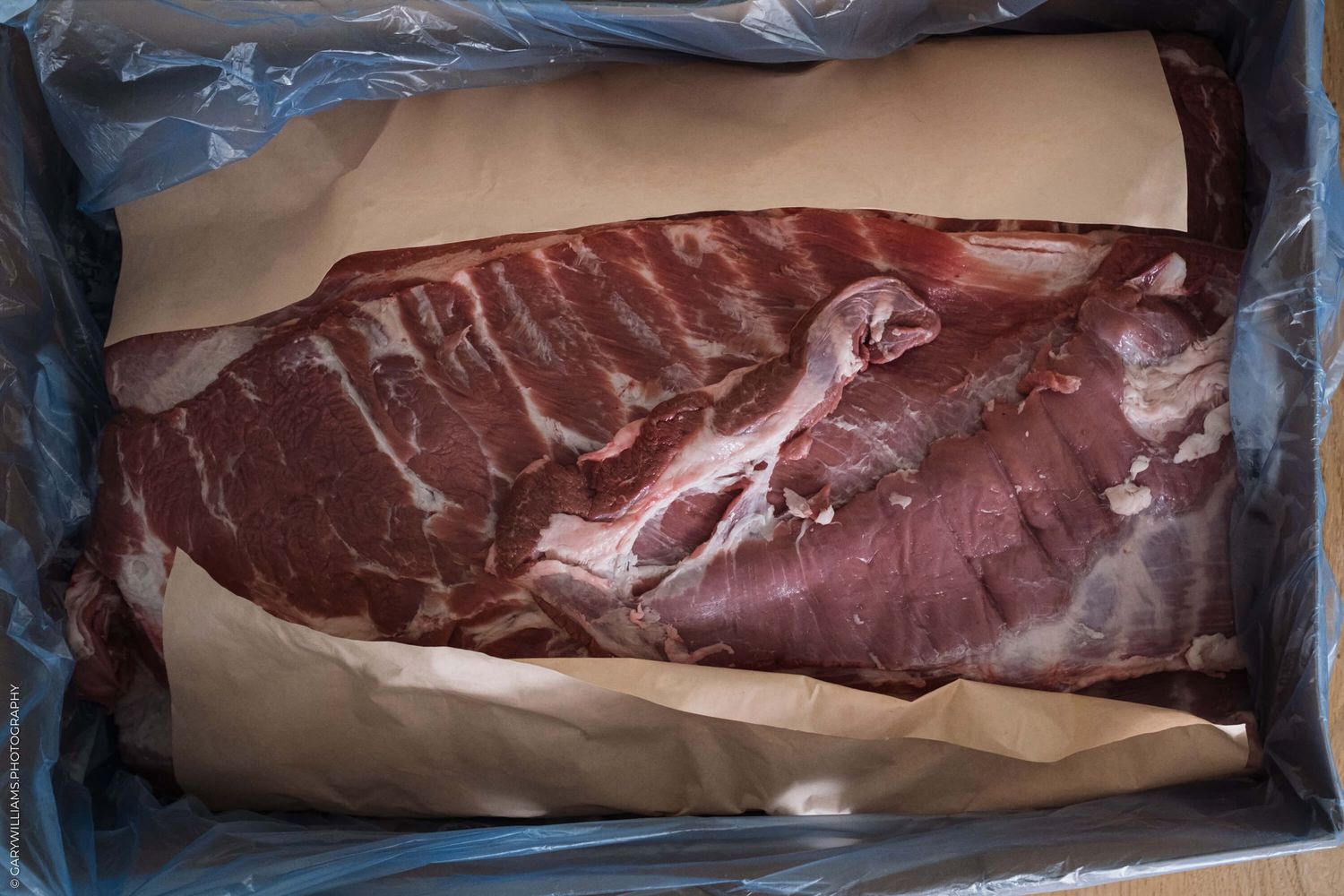 A raw beef strip loin steak with marbling sits on brown butcher paper.