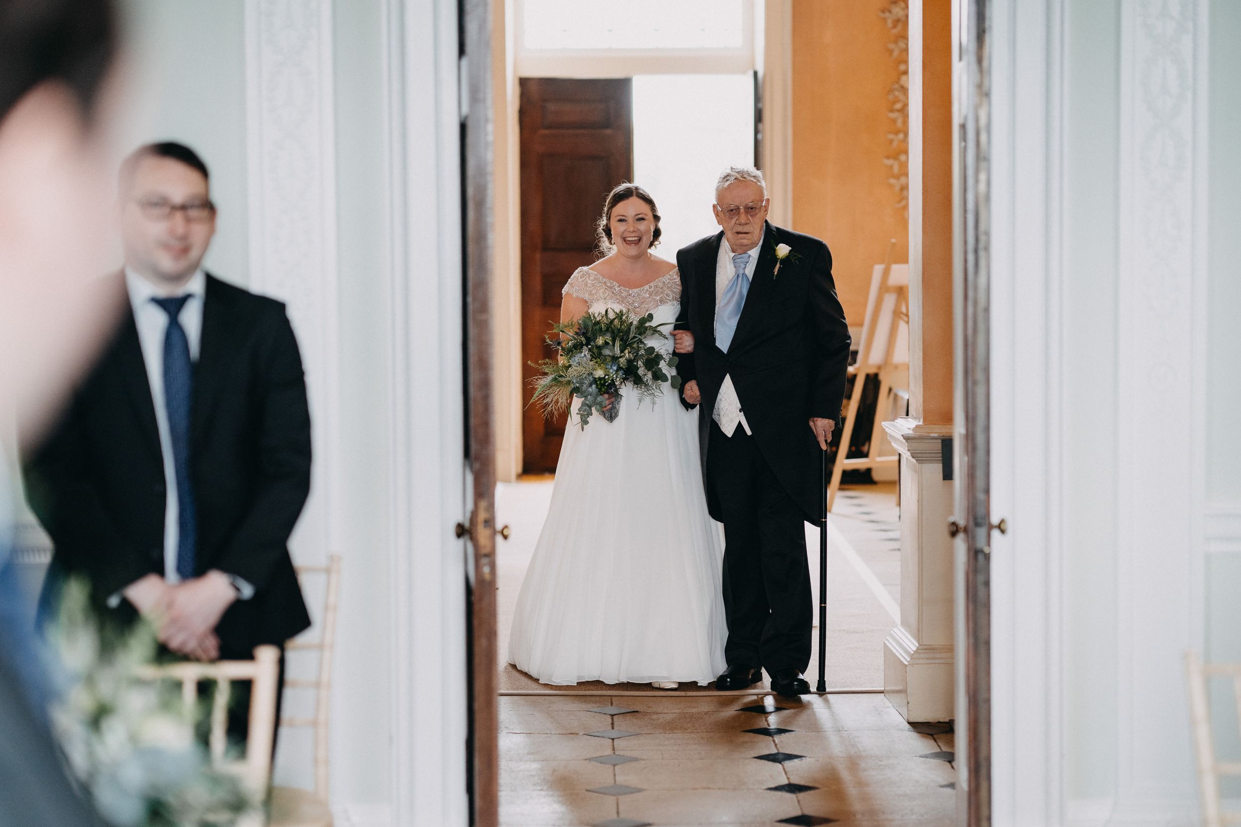 A formal procession through an elegant doorway in a classic interior with white walls.