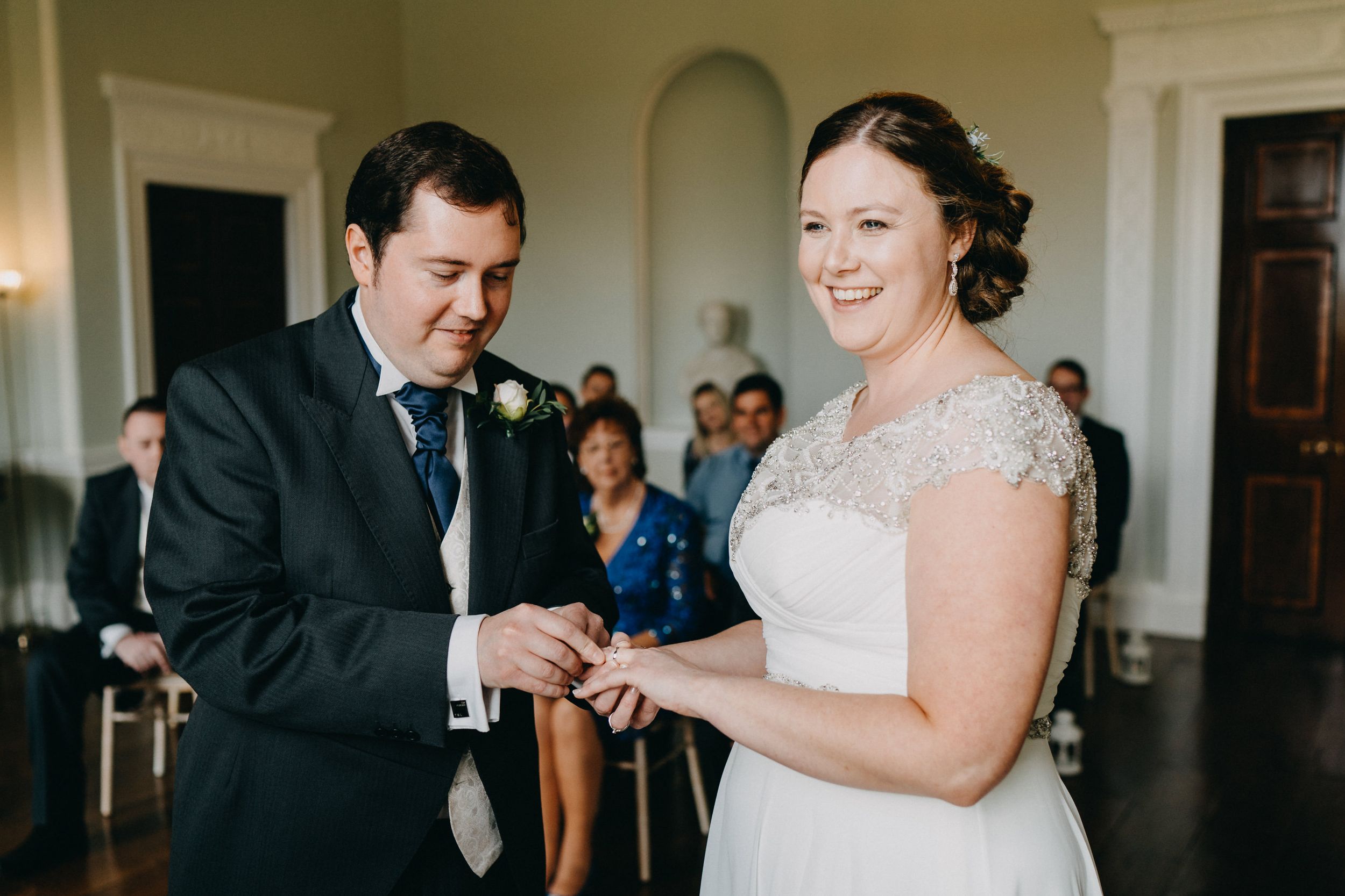 A formal ring exchange ceremony takes place in an elegant room with classic decor.