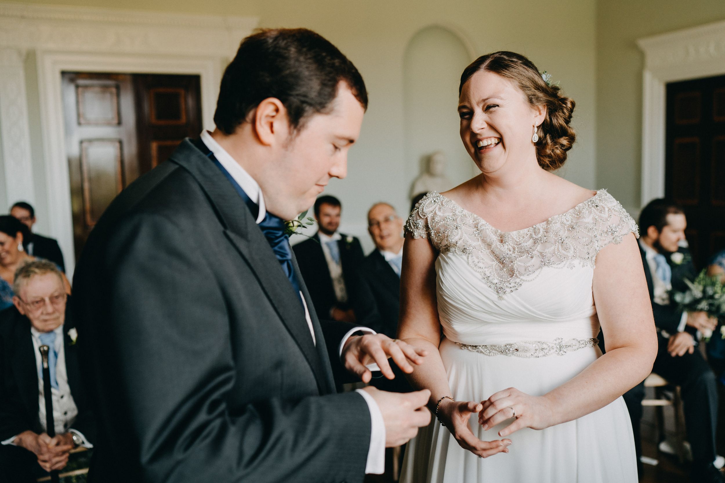 A joyful wedding ceremony moment during the exchange of rings in an elegant indoor venue.
