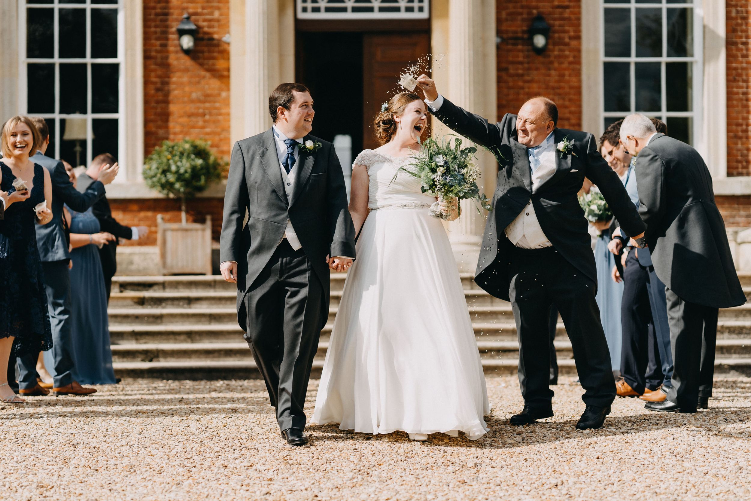 Wedding party celebrating on the steps of an elegant brick building.
