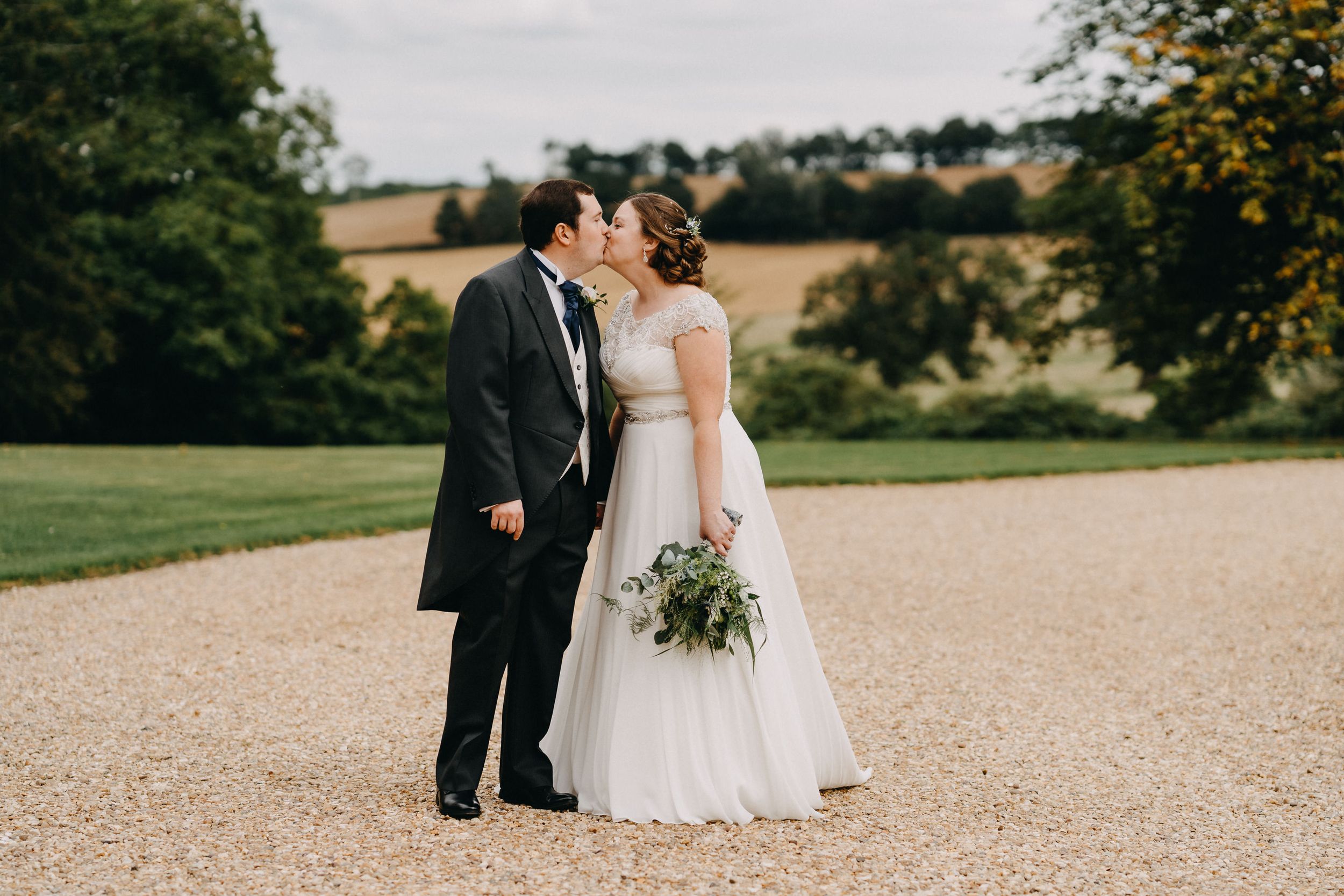 Newlyweds share an intimate moment on the grounds of an elegant estate.