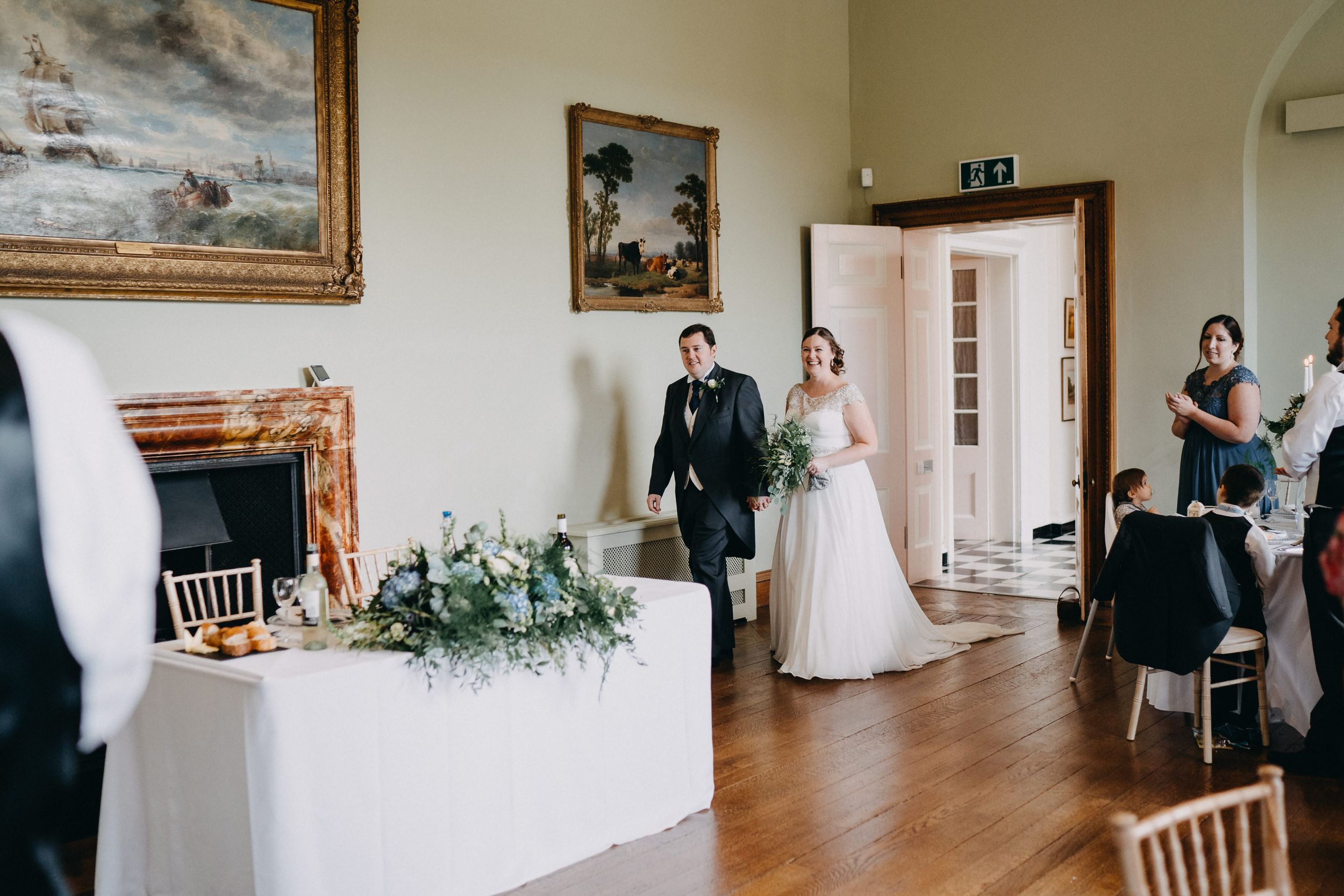 Wedding reception at Kelmarsh Hall room with elegant decor, artwork, and floral arrangements.