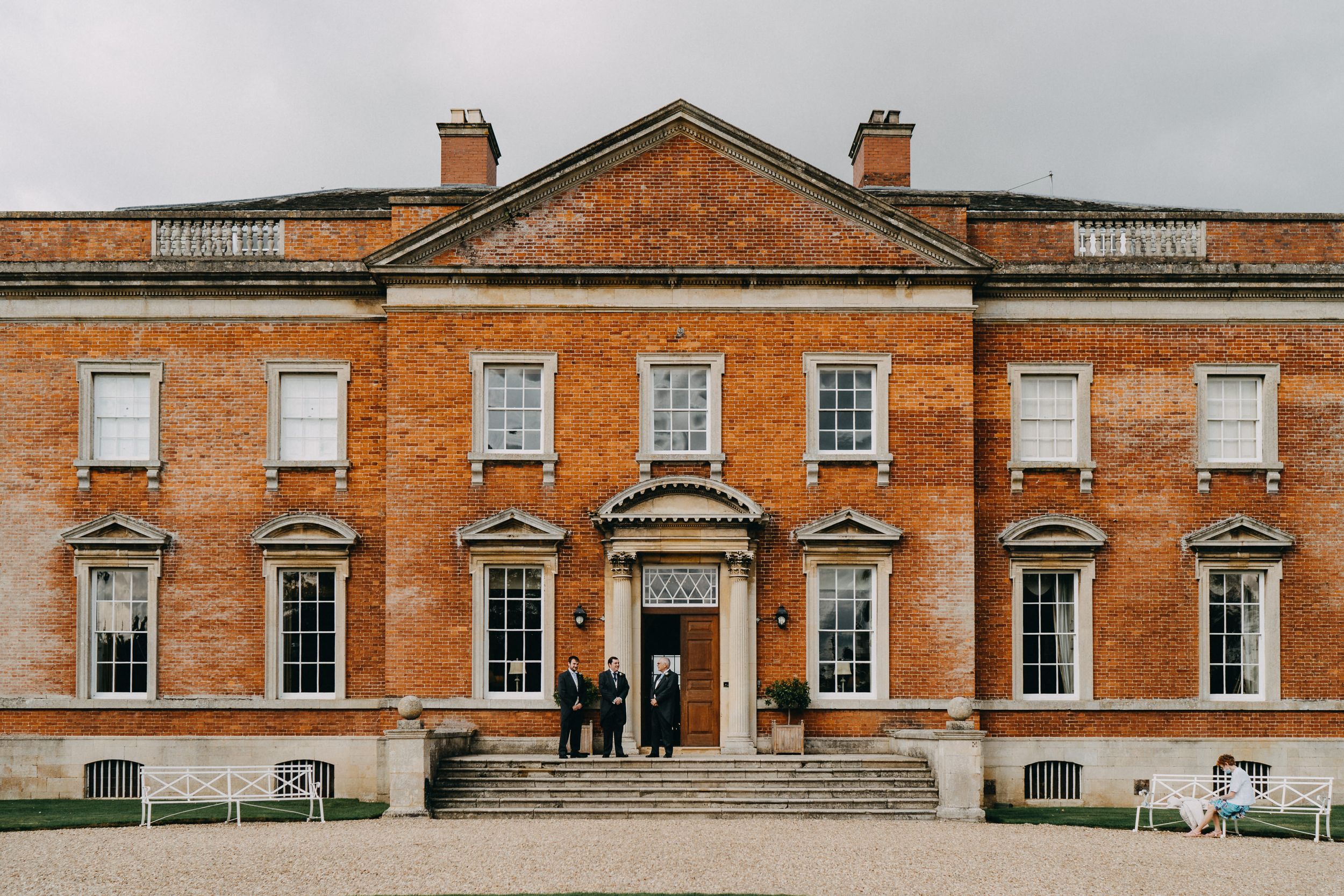 Symmetrical Georgian-style mansion of Kelmarsh Hall with red brick facade and classical columns.