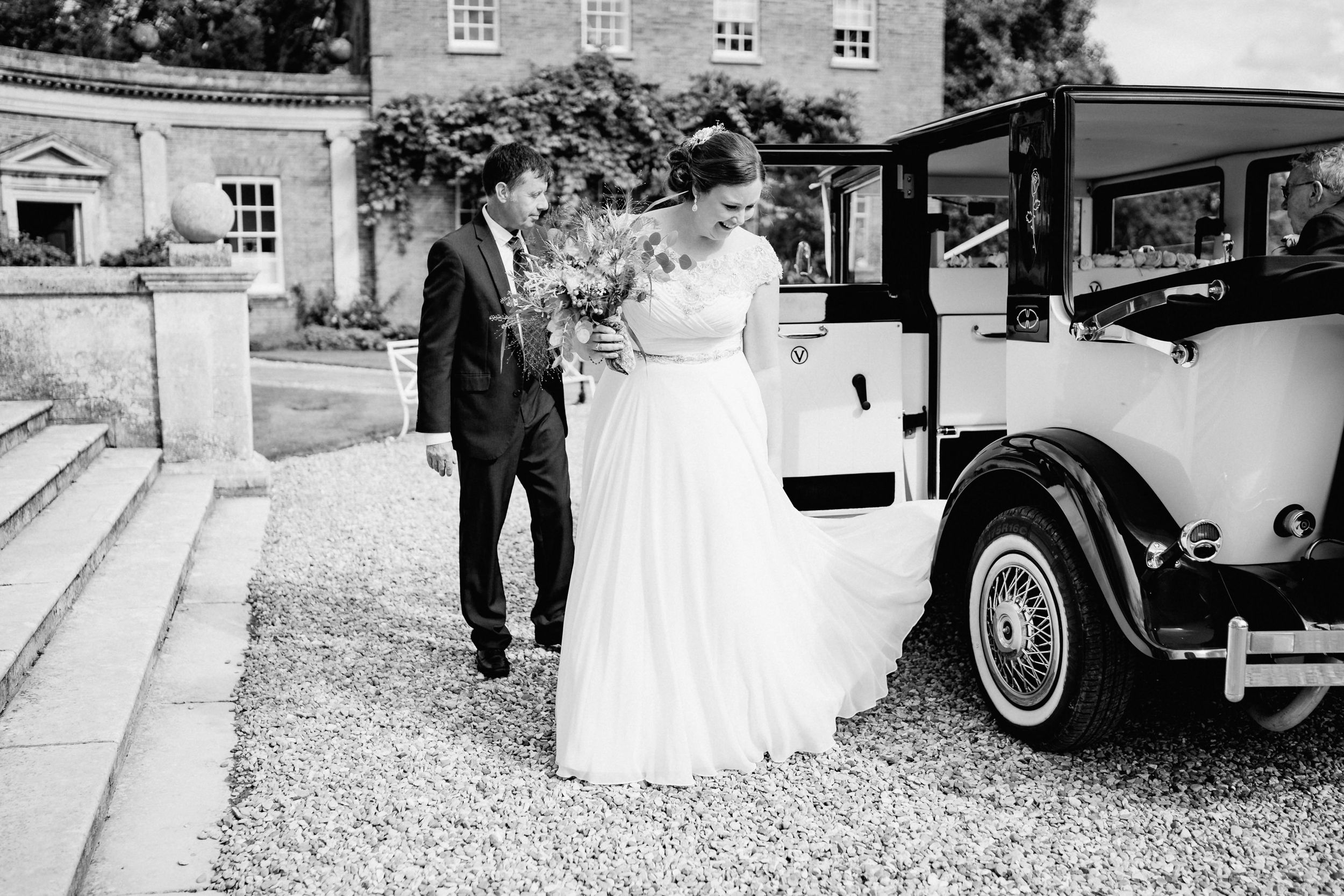 Classic vintage car beside stone steps at elegant wedding venue.