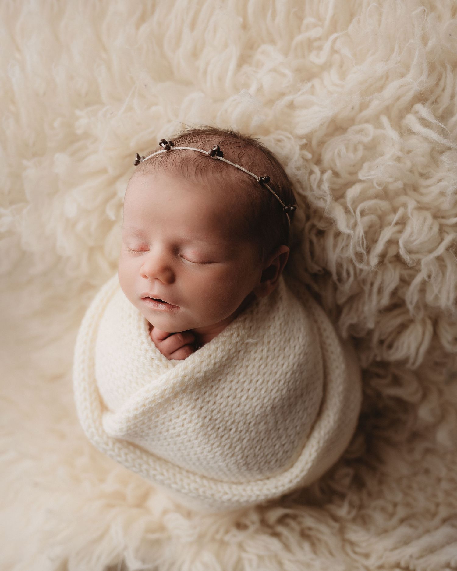 Professional photo of a newborn baby on a cream flokati rug
