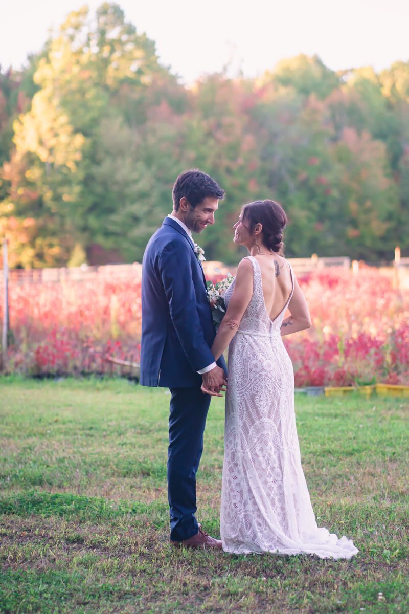 A bride and groom stand before a colorful field at a Michigan Fall wedding near dusk.