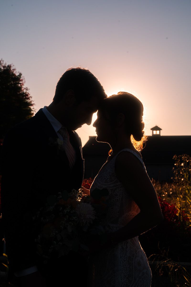 A silhouette of the bride and groom is captured at f22 as the sun is just beginning to set over the edge of the treeline.