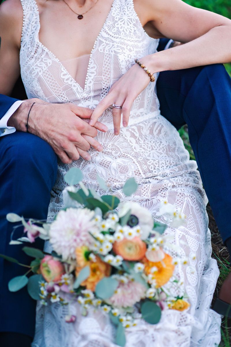 The interlocked hands of the bride and groom are featured as they cuddle during golden hour.