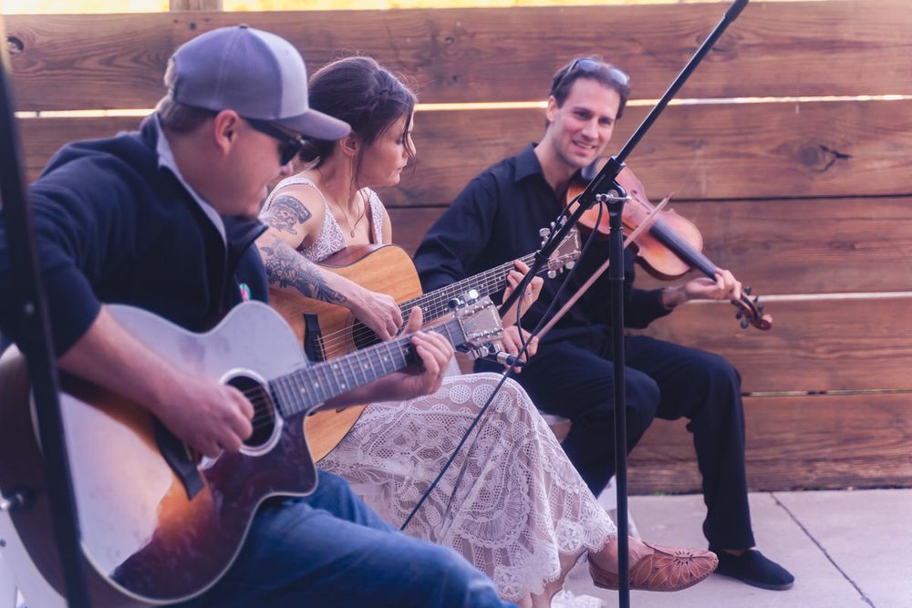 The bride plays guitar with Josh Holcomb on violin to entertain her wedding guests at her laid-back DIY, intimate reception event.