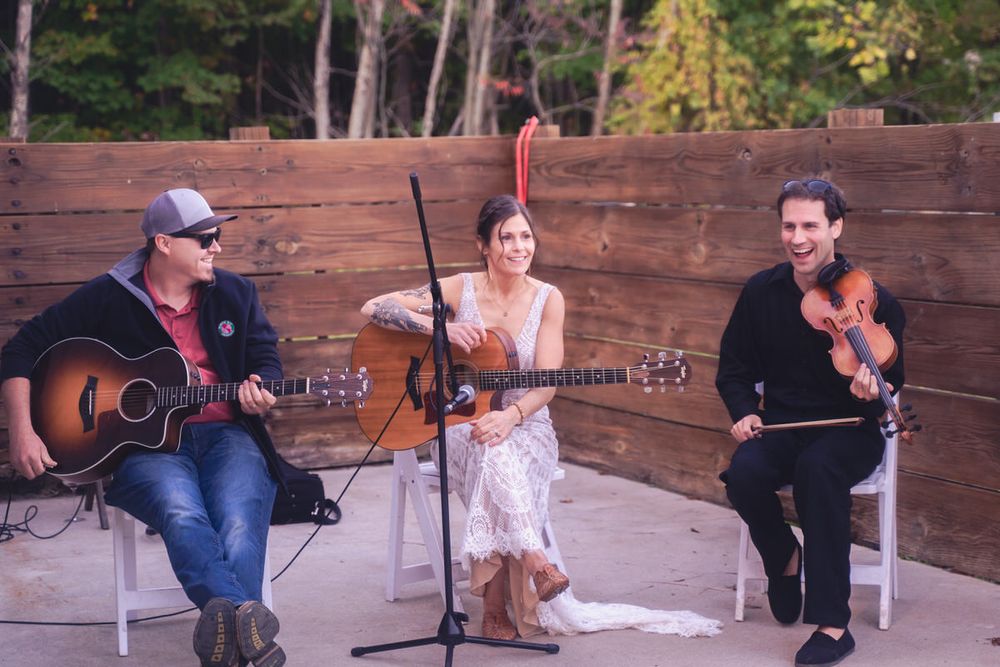 The bride plays guitar to entertain her wedding guests at her laid-back DIY, intimate reception event.