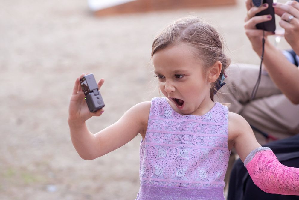A young wedding guest films herself with a professional action camera for a DIY wedding reception event in Southwest Michigan.