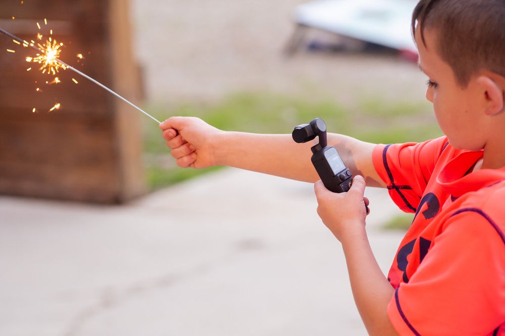 A young wedding guest films himself holding a sparkler with an osmo pocket for a DIY wedding reception event in Southwest Michigan.